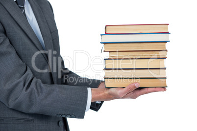 Mid section of businessman holding stack of books