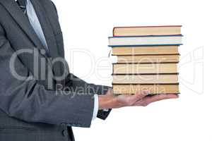 Mid section of businessman holding stack of books