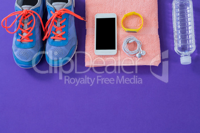 Sneakers, water bottle, towel, mobile phone with headphones and wristband