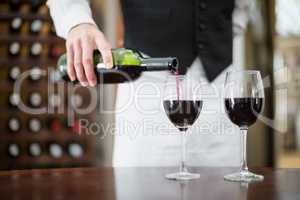 Male waiter pouring wine in wine glasses