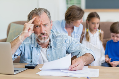 Worried man calculating bills on the laptop in living room