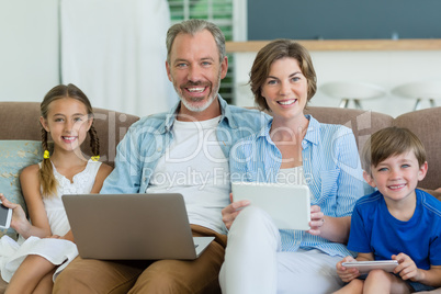 Happy family using mobile phone, digital tablet and laptop in living room