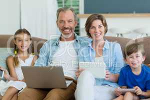 Happy family using mobile phone, digital tablet and laptop in living room