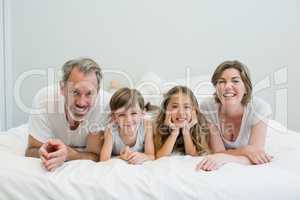 Portrait of smiling family lying on bed in bedroom