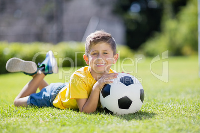 Boy lying on grass with football in the park