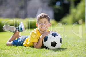 Boy lying on grass with football in the park