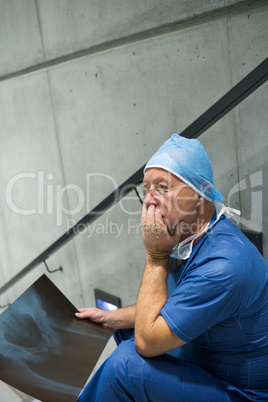 Worried male surgeon holding x-ray on staircase