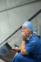 Worried male surgeon holding x-ray on staircase