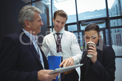 Businesspeople using digital tablet while having coffee