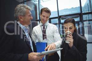 Businesspeople using digital tablet while having coffee