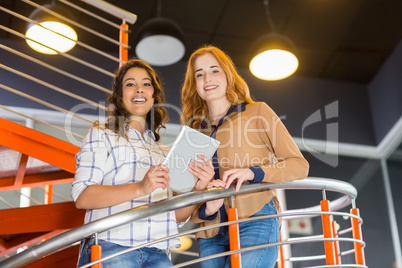 Portrait of happy female executive using digital tablet on staircase