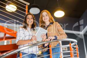 Portrait of happy female executive using digital tablet on staircase