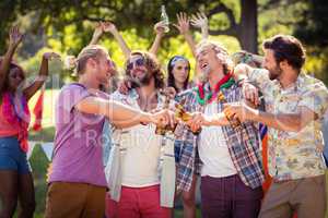 Happy friends toasting beer bottles at campsite