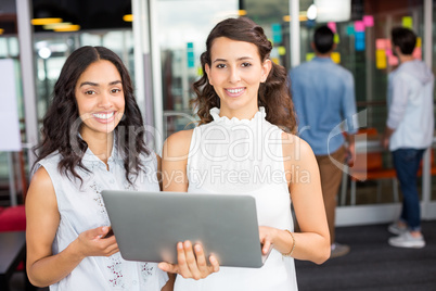 Portrait of happy female executives using laptop