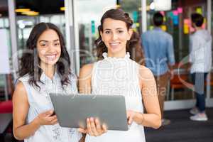 Portrait of happy female executives using laptop