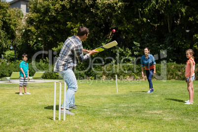 Happy family playing cricket in park