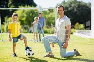 Father and son playing football in park on a sunny day