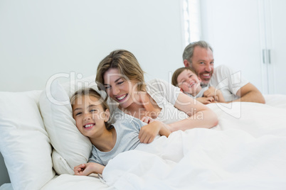 Happy family lying together on bed in bedroom at home
