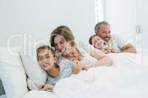 Happy family lying together on bed in bedroom at home