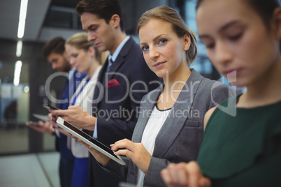 Business executives using electronic devices in corridor