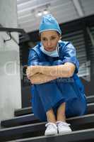 Thoughtful female surgeon sitting on staircase