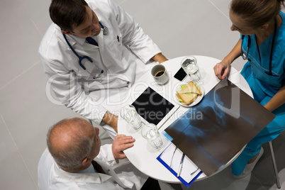 High angle view of doctors and surgeon examining x-ray while having breakfast