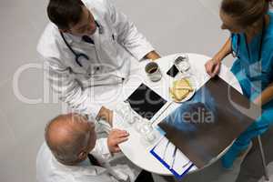 High angle view of doctors and surgeon examining x-ray while having breakfast
