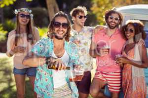 Happy man pouring beer in a glass while his friends standing in background