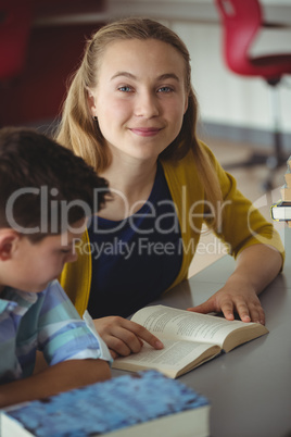 Smiling school kids reading books in library at school