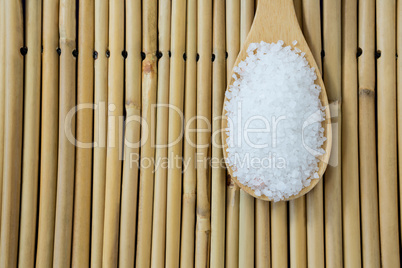 Salt in wooden scoop kept on bamboo mat