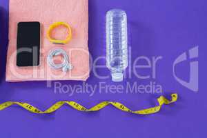 Water bottle, towel, measuring tape, mobile phone with headphones and fitness band