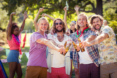 Happy friends toasting beer bottles at campsite