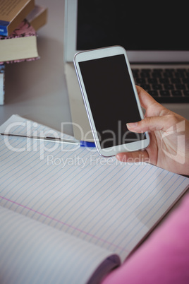 Schoolgirl using mobile phone in library