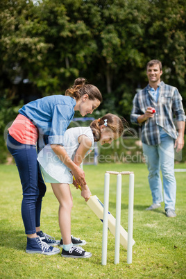 Family playing cricket in park