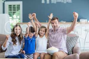 Family cheering while watching tv in living room at home