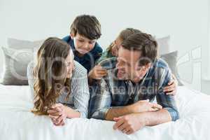 Family playing on bed in bedroom at home