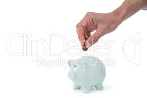 Hand inserting coin in piggy bank