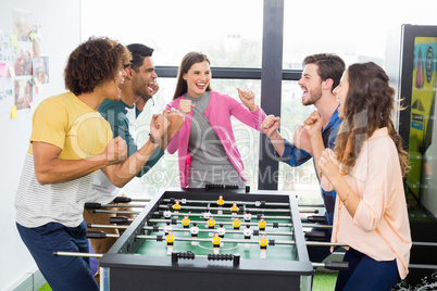 Happy executives cheering while playing table football