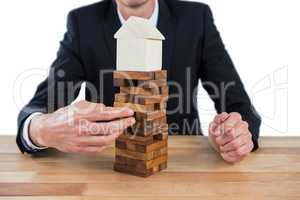 Businessman arranging building blocks with house model on top