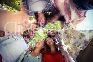 Happy friends forming a huddle in park