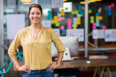 Portrait of smiling female executive standing with hands on hip