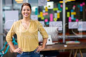 Portrait of smiling female executive standing with hands on hip