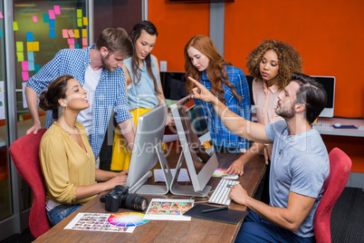 Graphic designers interacting with each other while working at desk