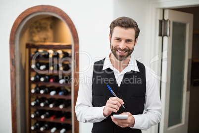 Male waiter smiling while taking down order