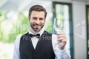 Male waiter holding empty wine glass in the restaurant