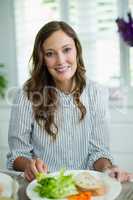 Portrait of smiling woman sitting at dining table
