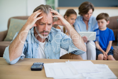 Worried man calculating bills in living room