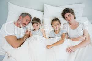 Happy family lying together on bed in bedroom at home