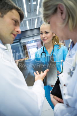 Medical team discussing over x-ray report in corridor