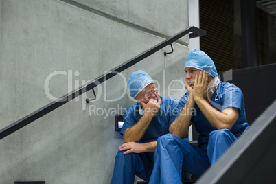 Worried male surgeons sitting on staircase